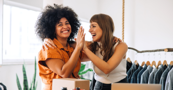 Two women smiling and high fiving